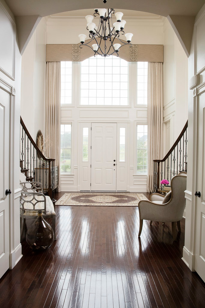 This is an example of a transitional foyer in DC Metro with dark hardwood floors, a single front door, a white front door, white walls and brown floor.