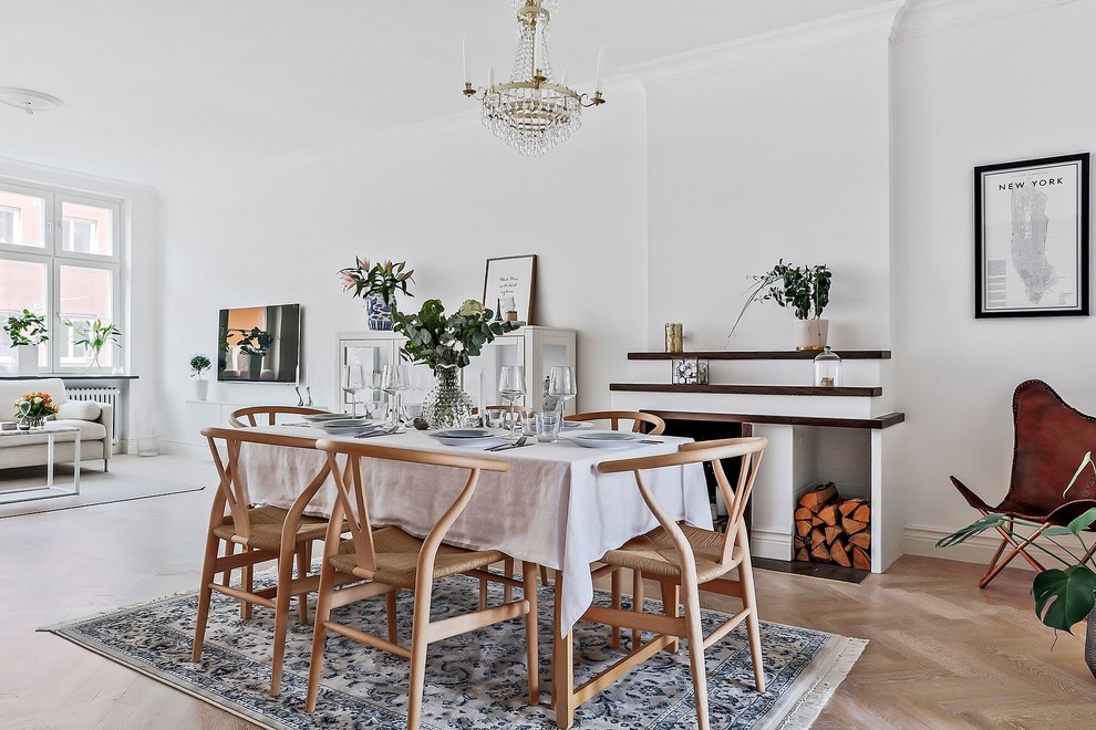 Inspiration for a scandinavian dining room in Malmo with white walls, light hardwood floors, a standard fireplace and a wood fireplace surround.