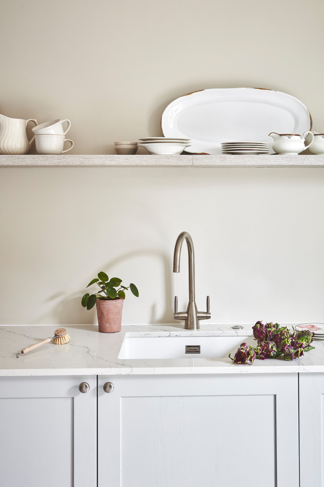 Foto på en stor funkis vita linjär tvättstuga enbart för tvätt, med en undermonterad diskho, skåp i shakerstil, grå skåp, bänkskiva i kvartsit och beige väggar