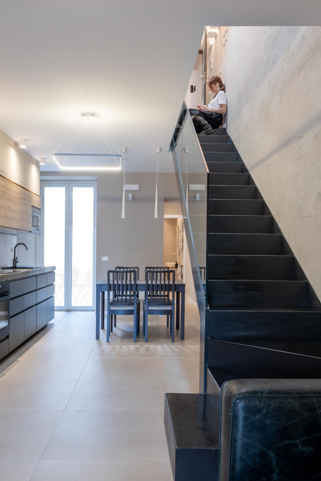 Imagen de escalera en L urbana de tamaño medio con escalones de metal, contrahuellas de metal, barandilla de vidrio y panelado
