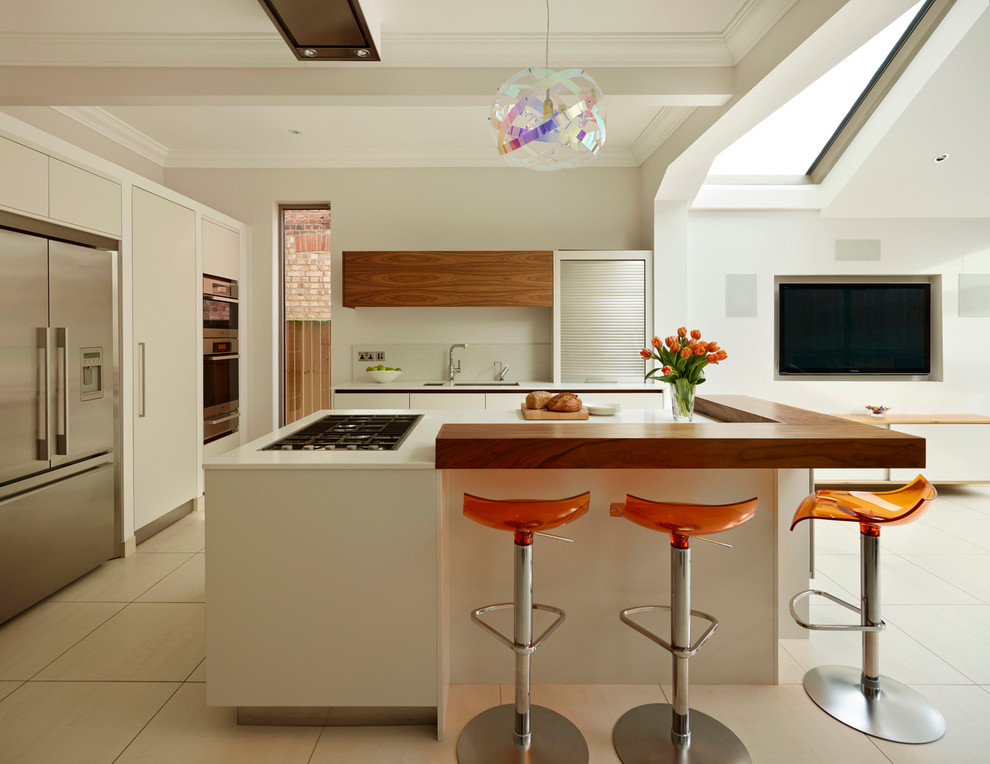 This is an example of a large contemporary l-shaped open plan kitchen in London with an undermount sink, flat-panel cabinets, white cabinets, quartz benchtops, white splashback, glass sheet splashback, stainless steel appliances and with island.