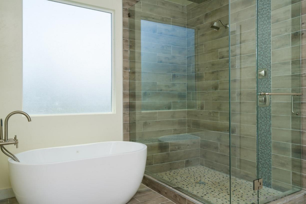 Klassisk inredning av ett stort en-suite badrum, med ett fristående badkar, våtrum, brun kakel, beige väggar, brunt golv och dusch med gångjärnsdörr