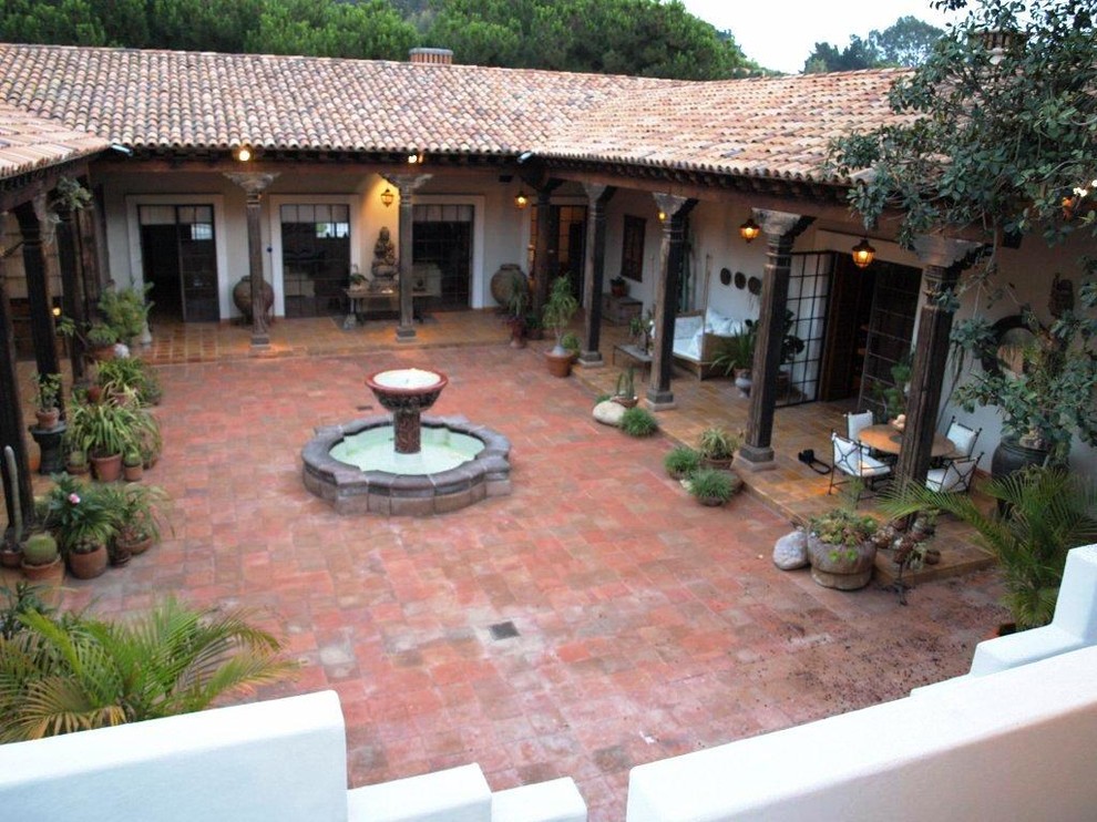 This is an example of a large asian courtyard patio in San Diego with a water feature, tile and a roof extension.