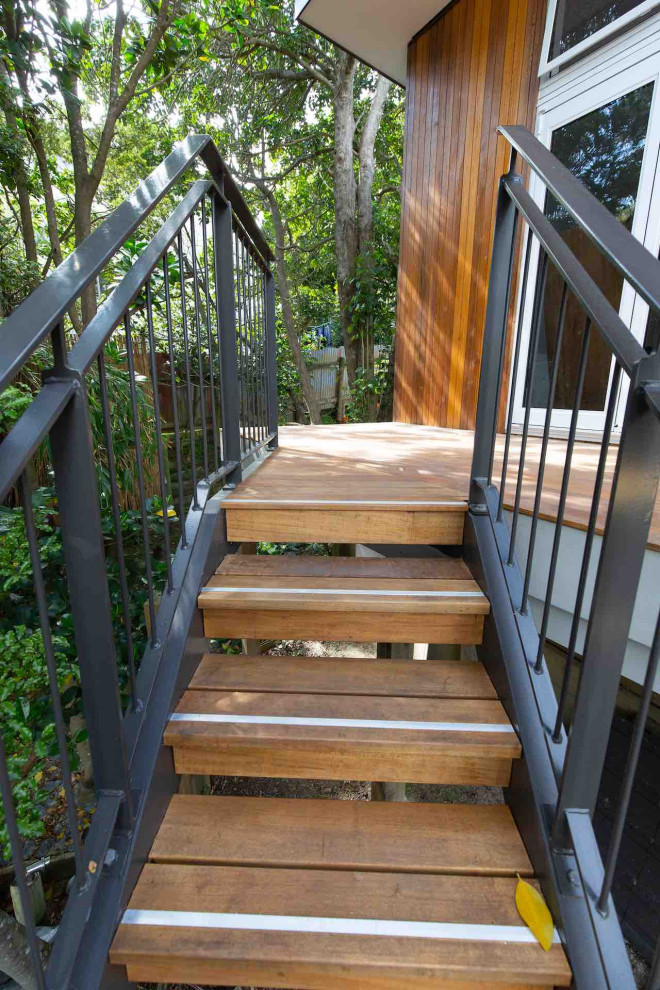 This is an example of a mid-sized industrial wood l-shaped staircase in Auckland with wood risers and metal railing.