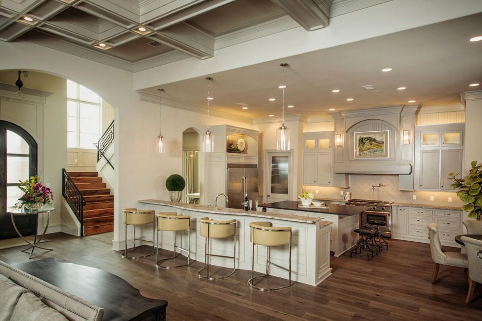 Inspiration for a large transitional u-shaped dark wood floor and brown floor open concept kitchen remodel in Austin with white cabinets, an island, shaker cabinets, granite countertops, beige backsplash and stainless steel appliances