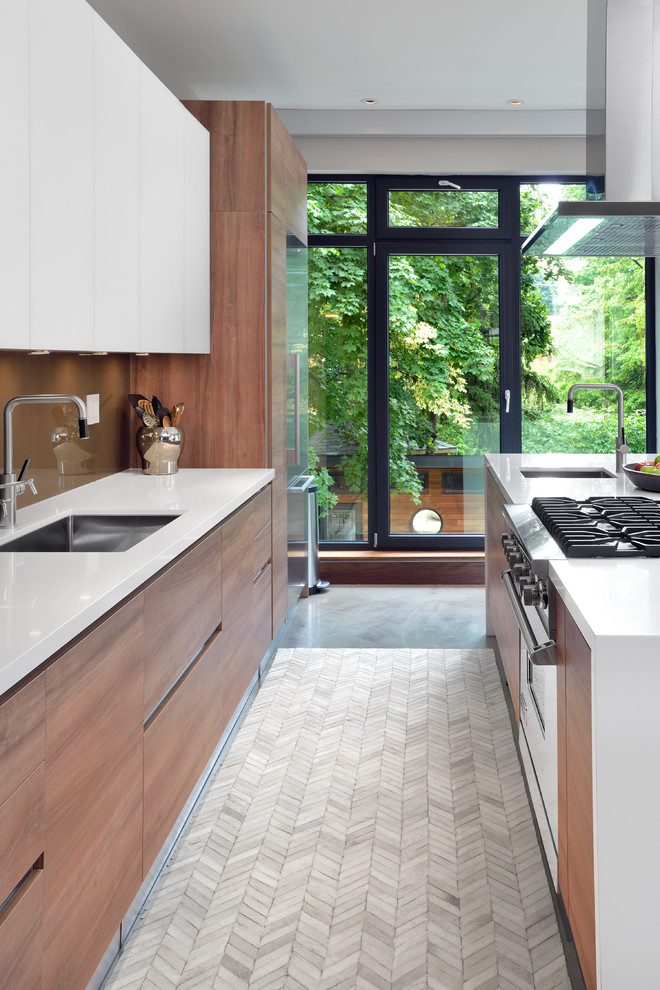 Design ideas for a contemporary galley open plan kitchen in Toronto with an undermount sink, flat-panel cabinets, medium wood cabinets, brown splashback, glass sheet splashback and stainless steel appliances.