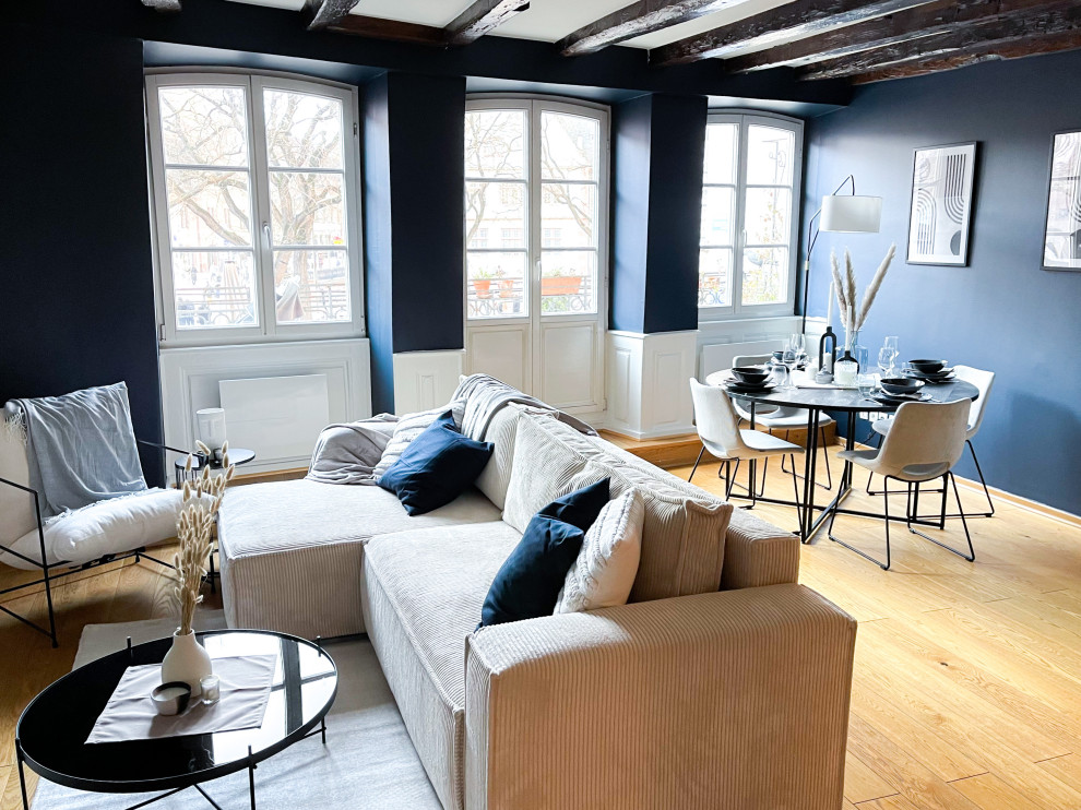 Mittelgroßes, Offenes Klassisches Wohnzimmer ohne Kamin mit blauer Wandfarbe, hellem Holzboden, freistehendem TV, gelbem Boden und freigelegten Dachbalken in Straßburg