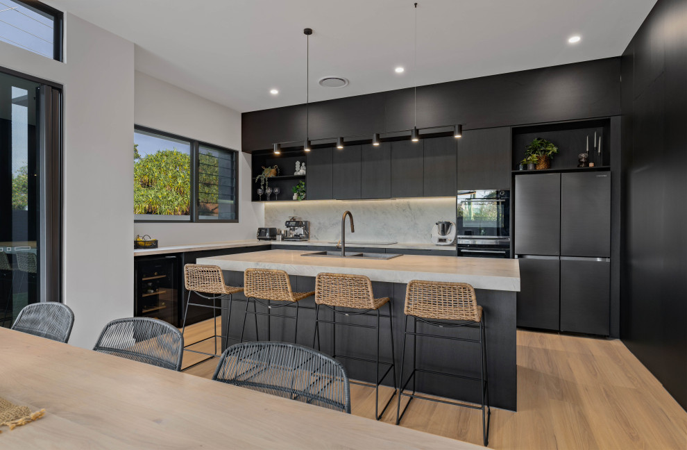 This is an example of a contemporary eat-in kitchen in Sunshine Coast with a double-bowl sink, black cabinets, grey splashback, stone slab splashback, black appliances, with island and grey benchtop.
