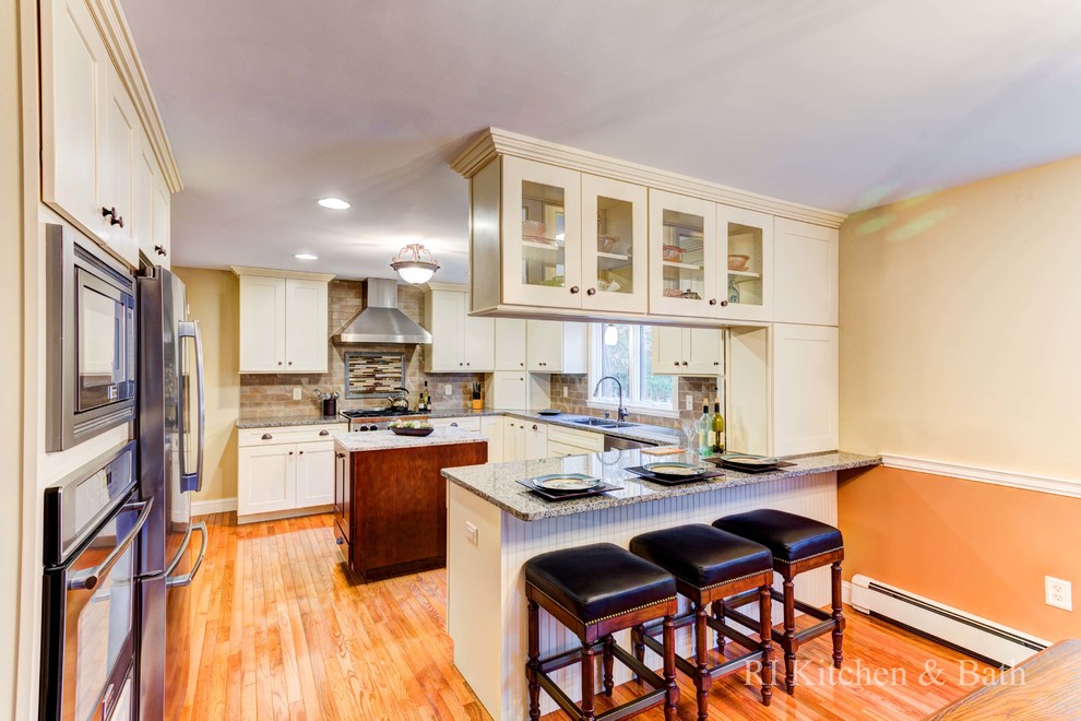 Example of a large transitional u-shaped light wood floor eat-in kitchen design in Providence with an undermount sink, shaker cabinets, beige cabinets, granite countertops, brown backsplash, porcelain backsplash, stainless steel appliances and an island