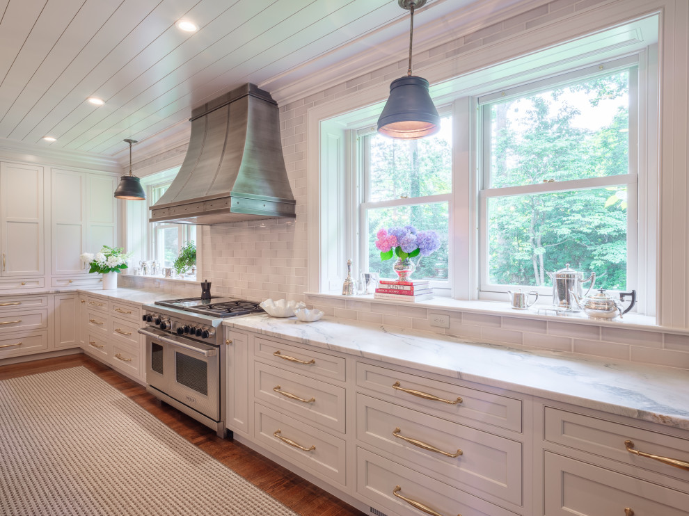 Expansive transitional l-shaped eat-in kitchen in New York with an integrated sink, recessed-panel cabinets, grey cabinets, quartzite benchtops, grey splashback, subway tile splashback, stainless steel appliances, medium hardwood floors, with island, brown floor and white benchtop.