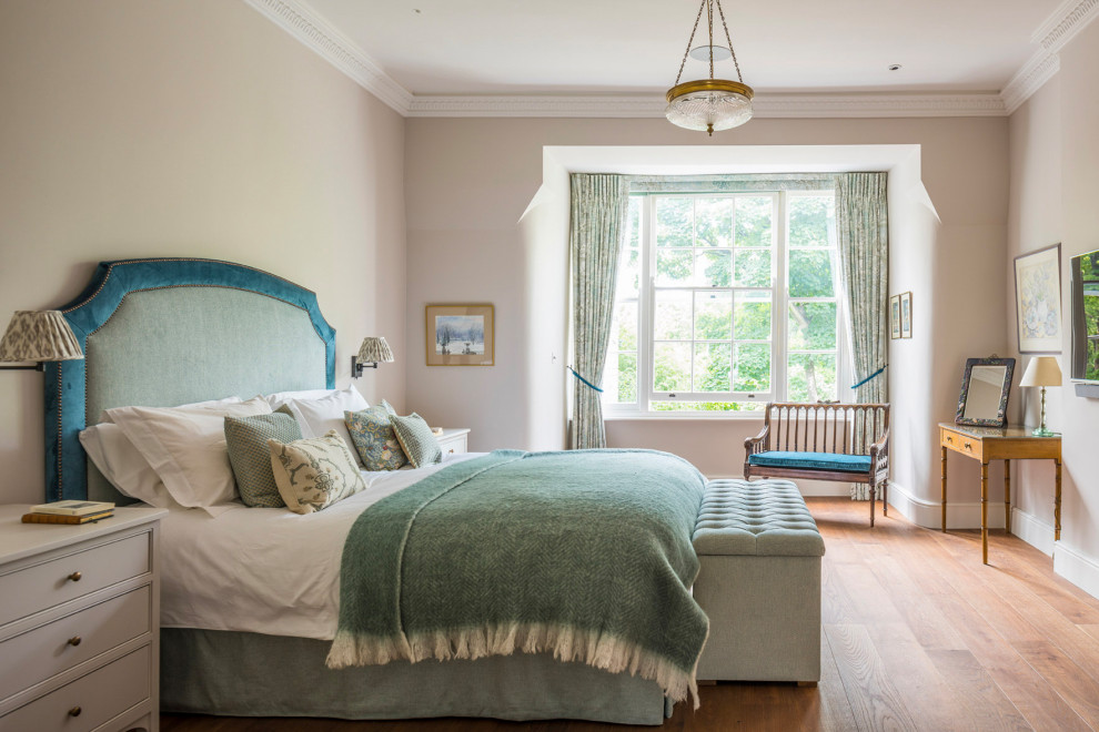 Design ideas for a large classic master bedroom in London with beige walls, medium hardwood flooring and brown floors.