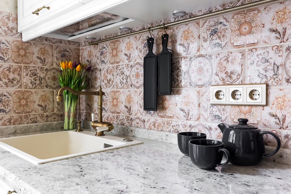 Exempel på ett litet klassiskt grå linjärt grått kök och matrum, med en undermonterad diskho, luckor med upphöjd panel, vita skåp, marmorbänkskiva, flerfärgad stänkskydd, stänkskydd i keramik, integrerade vitvaror, laminatgolv, en köksö och brunt golv