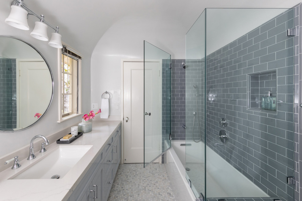 Bild på ett mellanstort vintage vit vitt badrum med dusch, med luckor med profilerade fronter, vita skåp, en hörndusch, vit kakel, keramikplattor, vita väggar, klinkergolv i porslin, ett undermonterad handfat, marmorbänkskiva, grått golv och dusch med gångjärnsdörr