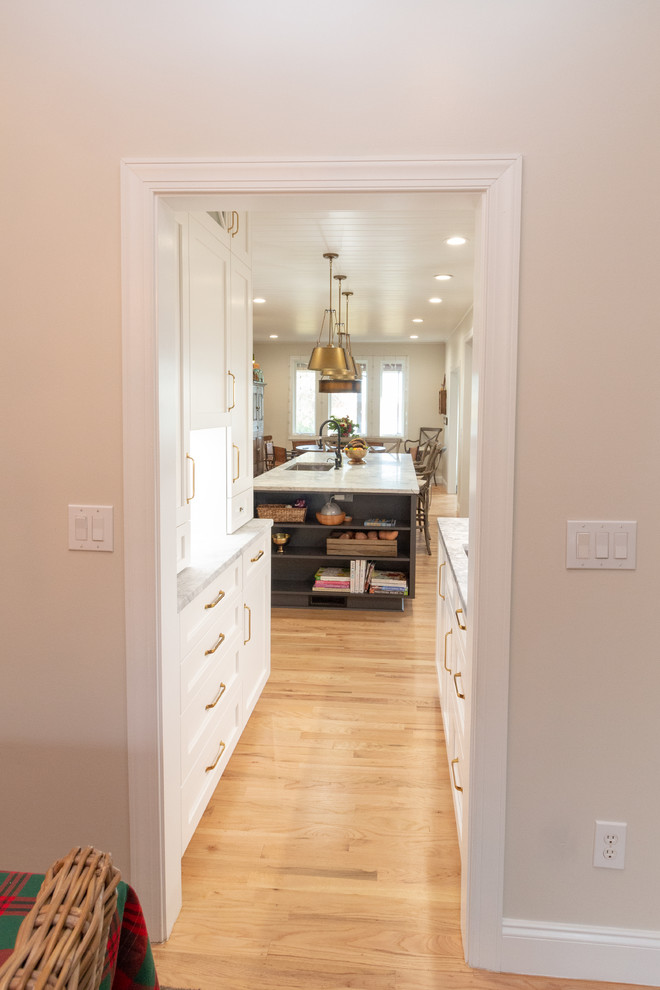 Example of a large l-shaped eat-in kitchen design with shaker cabinets, white cabinets, granite countertops, an island and white countertops