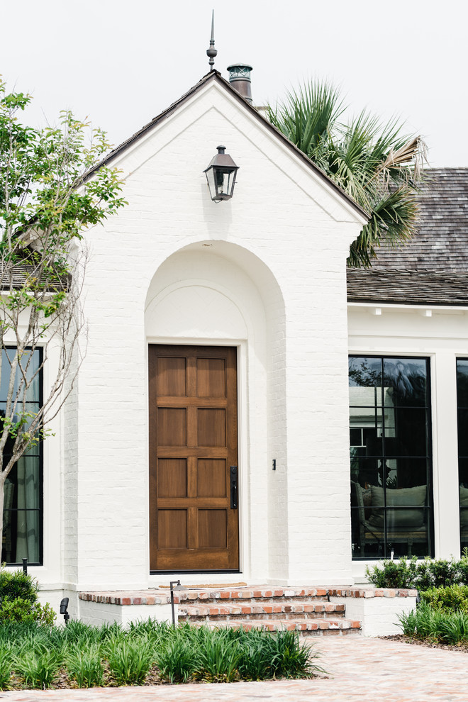 Photo of a large mediterranean front door in Jacksonville with white walls, brick floors, a single front door, a medium wood front door and red floor.