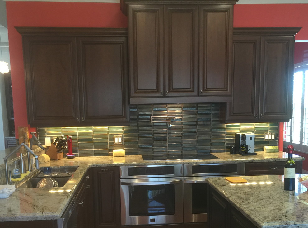 Kitchen - traditional kitchen idea with glass-front cabinets, dark wood cabinets, granite countertops, multicolored backsplash and glass tile backsplash