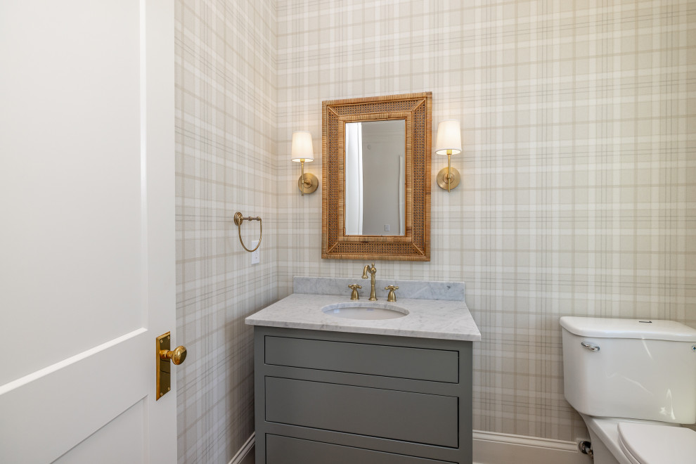 Traditional powder room in Other with beaded inset cabinets, grey cabinets, a two-piece toilet, light hardwood floors, an integrated sink, marble benchtops, a freestanding vanity and wallpaper.