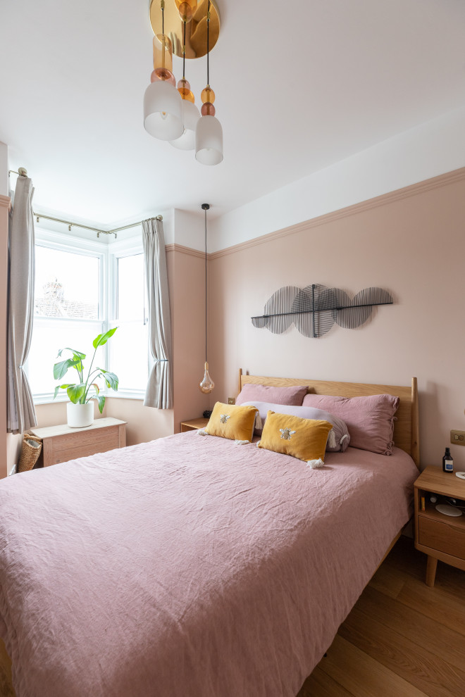 ロンドンにある中くらいなコンテンポラリースタイルのおしゃれな主寝室 (ピンクの壁、無垢フローリング、標準型暖炉、茶色い床、照明) のレイアウト