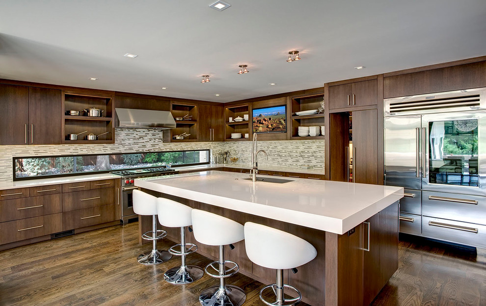 Contemporary l-shaped kitchen in Kansas City with an undermount sink, flat-panel cabinets, dark wood cabinets, grey splashback, stainless steel appliances, dark hardwood floors, with island, brown floor and white benchtop.