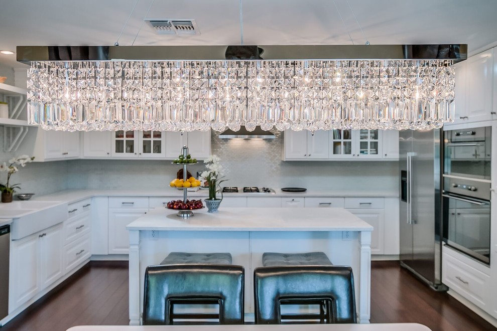 Example of a mid-sized transitional u-shaped medium tone wood floor and brown floor open concept kitchen design in Phoenix with raised-panel cabinets, white cabinets, quartz countertops, white backsplash, matchstick tile backsplash, stainless steel appliances and an island