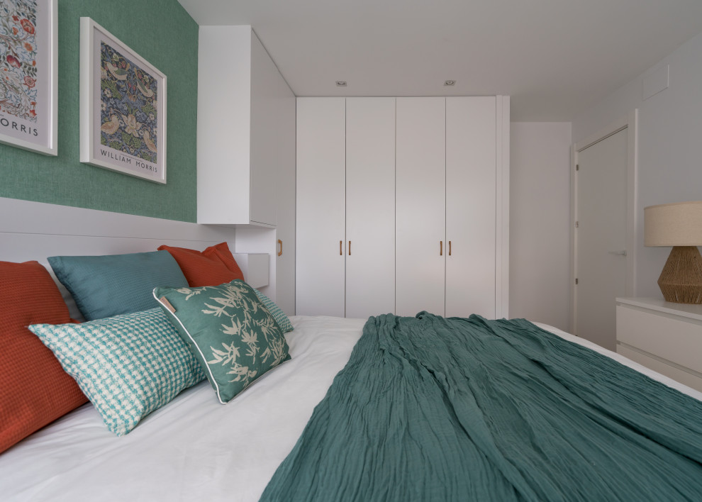 Modelo de dormitorio principal y blanco y madera mediterráneo pequeño con paredes verdes, suelo laminado y suelo marrón