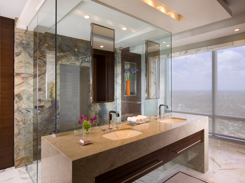 This is an example of a large contemporary bathroom in Miami with a drop-in sink, beige tile, stone tile, marble floors, quartzite benchtops, a double shower, multi-coloured walls and dark wood cabinets.