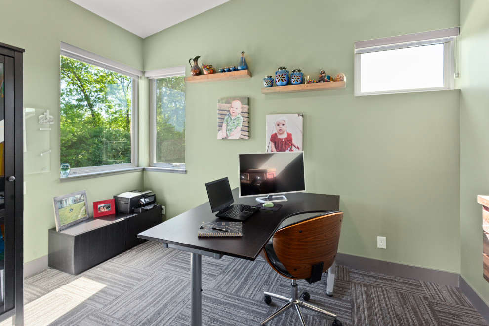 Immagine di un grande ufficio moderno con pareti verdi, moquette, scrivania autoportante, pavimento grigio e soffitto a volta