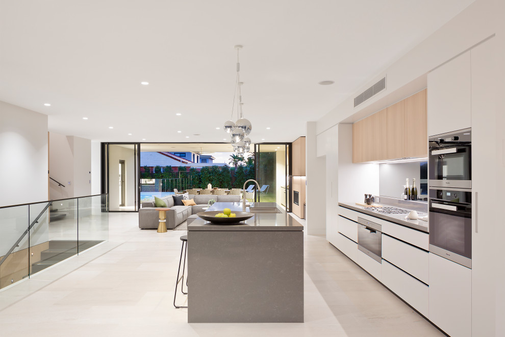 Inspiration for a contemporary galley kitchen in Sunshine Coast with an undermount sink, flat-panel cabinets, white cabinets, stainless steel appliances, light hardwood floors, with island, beige floor and grey benchtop.