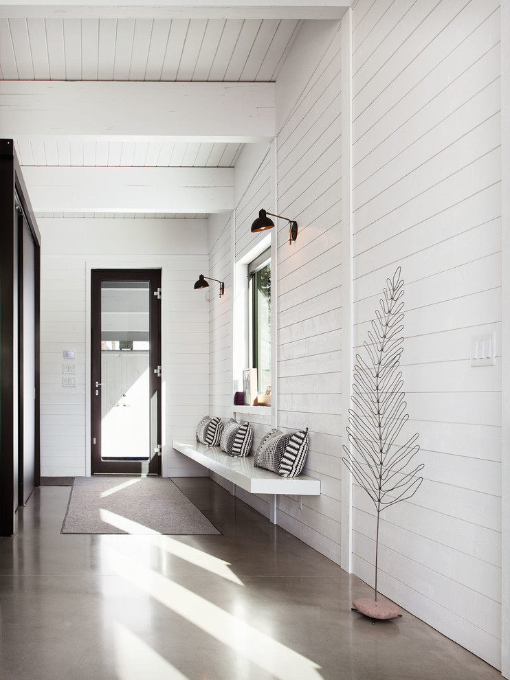 This is an example of a contemporary hallway in Montreal with white walls, concrete floors and grey floor.