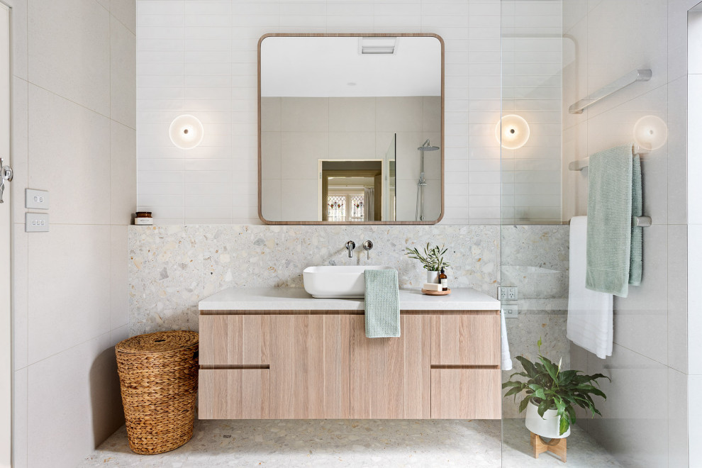 Inredning av ett modernt mellanstort vit vitt en-suite badrum, med släta luckor, skåp i ljust trä, en öppen dusch, en vägghängd toalettstol, grå kakel, tunnelbanekakel, grå väggar, cementgolv, ett fristående handfat, bänkskiva i kalksten, grått golv och med dusch som är öppen