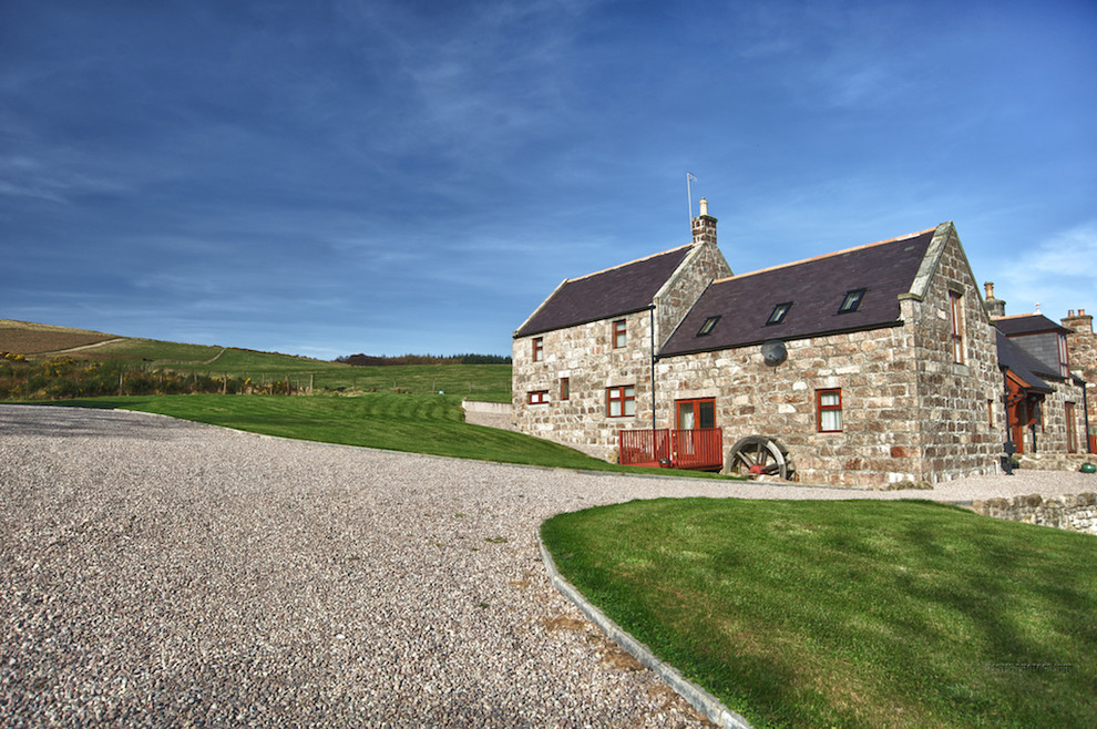 Photo of a country two-storey exterior in Other with stone veneer and a gable roof.