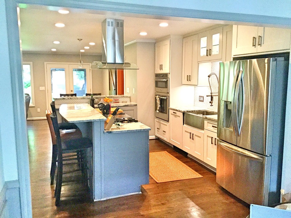 This is an example of a large contemporary u-shaped open plan kitchen in Atlanta with a farmhouse sink, shaker cabinets, white cabinets, quartzite benchtops, white splashback, subway tile splashback, stainless steel appliances, dark hardwood floors and with island.