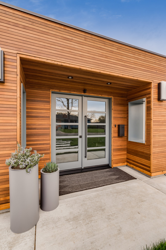 This is an example of a large modern front door in Sacramento with brown walls, concrete flooring, a double front door, a glass front door, grey floors, a wood ceiling, wood walls and feature lighting.