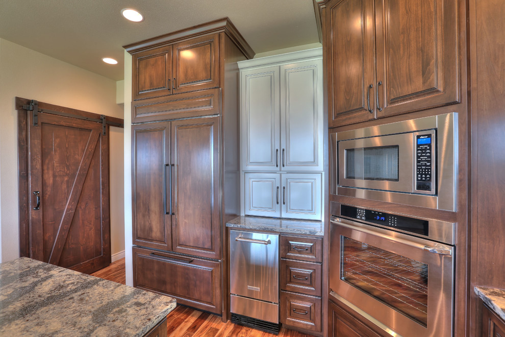 Eat-in kitchen - large transitional l-shaped medium tone wood floor eat-in kitchen idea in Seattle with an undermount sink, medium tone wood cabinets, granite countertops, brown backsplash, stainless steel appliances and an island