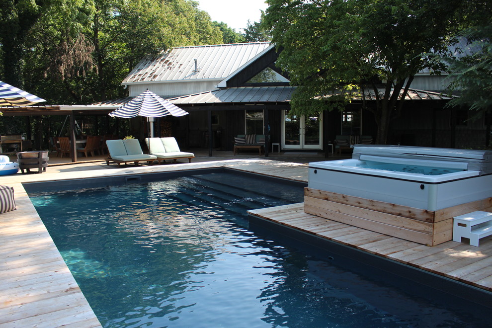 This is an example of a large country backyard l-shaped natural pool in Atlanta with a hot tub and decking.