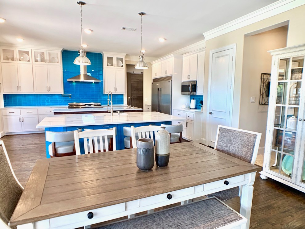 Photo of an expansive contemporary l-shaped eat-in kitchen in Dallas with shaker cabinets, white cabinets, quartz benchtops, blue splashback, multiple islands, white benchtop, an undermount sink, glass tile splashback, stainless steel appliances, dark hardwood floors and brown floor.