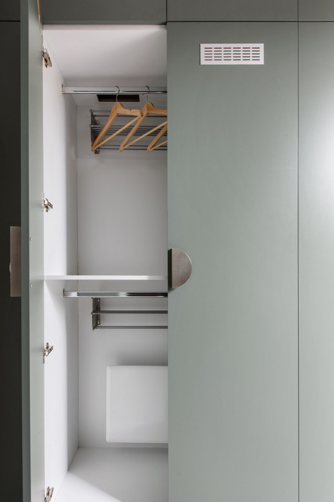 Inspiration for a mid-sized contemporary galley dedicated laundry room in Melbourne with a drop-in sink, flat-panel cabinets, green cabinets, limestone benchtops, white splashback, subway tile splashback, white walls, porcelain floors, an integrated washer and dryer, grey floor and white benchtop.