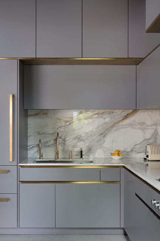 This is an example of a large contemporary l-shaped open plan kitchen in London with a submerged sink, flat-panel cabinets, grey cabinets, marble worktops, white splashback, marble splashback, stainless steel appliances, concrete flooring, an island, grey floors and white worktops.