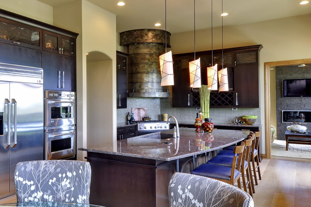 Inspiration for a large transitional l-shaped light wood floor and beige floor eat-in kitchen remodel in Omaha with a double-bowl sink, flat-panel cabinets, dark wood cabinets, granite countertops, green backsplash, mosaic tile backsplash, stainless steel appliances and an island
