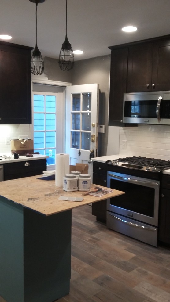 Mid-sized mountain style u-shaped porcelain tile eat-in kitchen photo in Indianapolis with a farmhouse sink, shaker cabinets, dark wood cabinets, wood countertops, white backsplash, ceramic backsplash, stainless steel appliances and an island