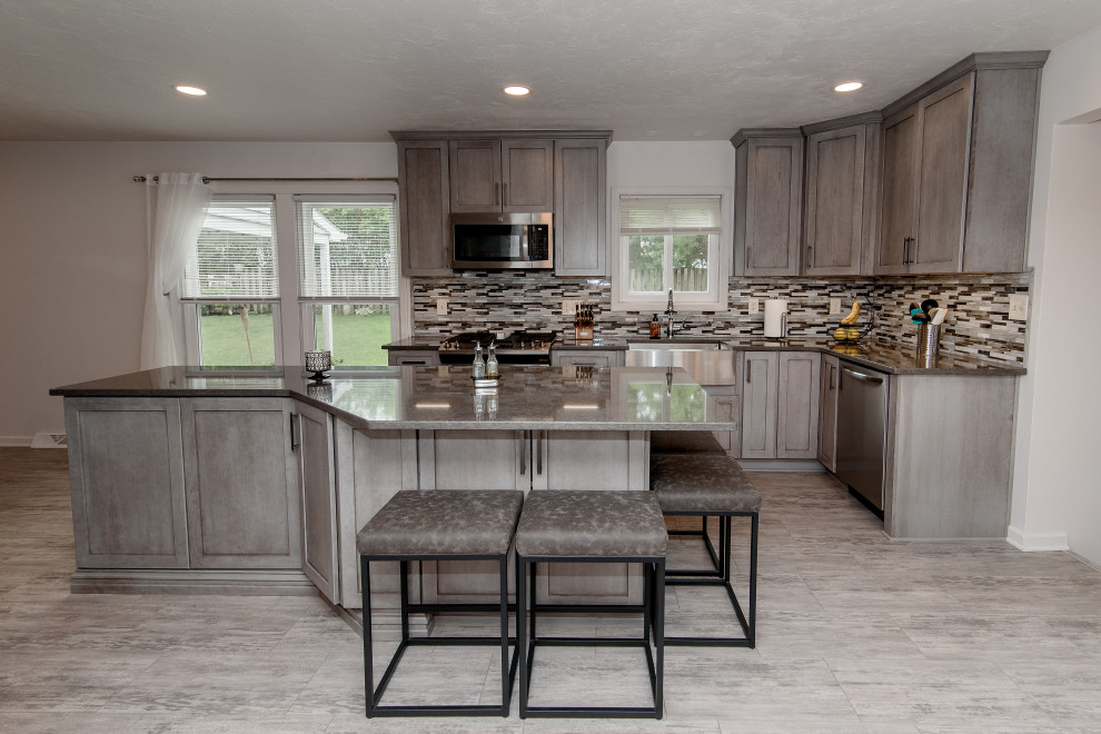 Large transitional u-shaped gray floor eat-in kitchen photo in Baltimore with a farmhouse sink, shaker cabinets, gray cabinets, quartz countertops, multicolored backsplash, glass tile backsplash, stainless steel appliances, an island and gray countertops