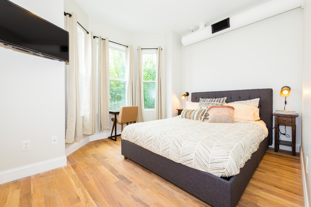 This is an example of a transitional bedroom in Boston with white walls, medium hardwood floors and brown floor.