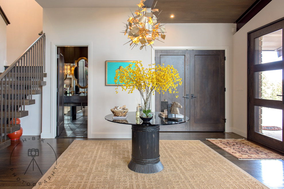 Large medium tone wood floor and brown floor foyer photo with white walls and a dark wood front door