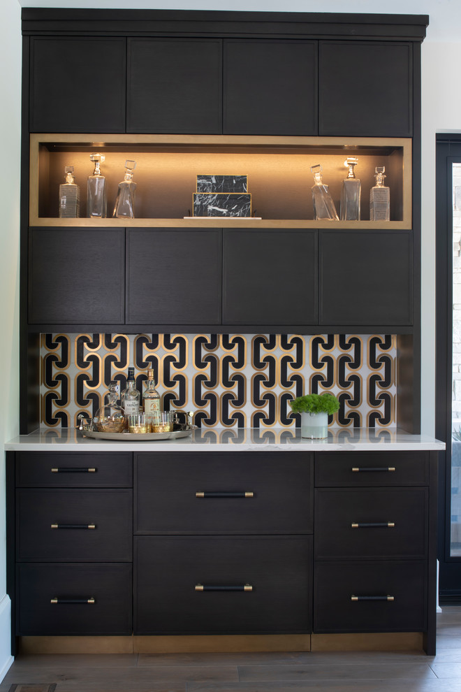Photo of a small country single-wall home bar in Minneapolis with brown cabinets, quartz benchtops, ceramic splashback, no sink, multi-coloured splashback, white benchtop and light hardwood floors.