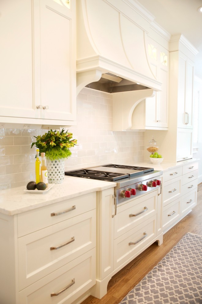 Eat-in kitchen - large transitional medium tone wood floor eat-in kitchen idea in Atlanta with an undermount sink, glass-front cabinets, white cabinets, quartz countertops, gray backsplash, subway tile backsplash, paneled appliances and an island