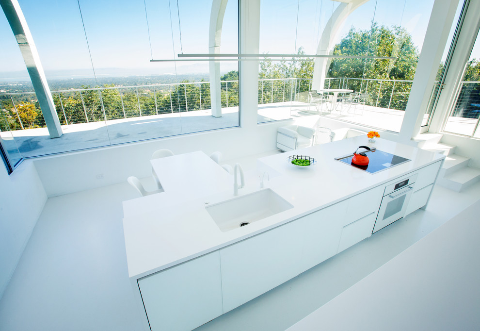 This is an example of an expansive modern galley separate kitchen in San Francisco with flat-panel cabinets, white cabinets, quartz benchtops, white appliances and with island.
