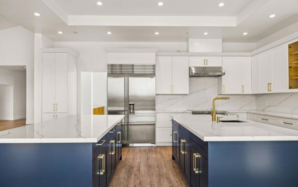 Moderne Küche mit blauen Schränken, Küchenrückwand in Weiß, zwei Kücheninseln und weißer Arbeitsplatte in Los Angeles