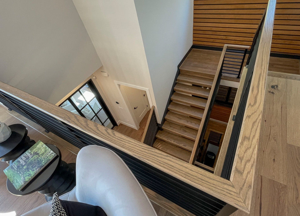 Imagen de escalera recta actual grande con escalones de madera, barandilla de varios materiales y panelado