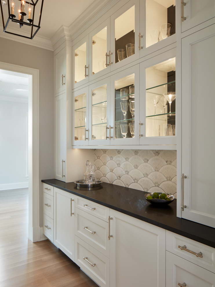 This is an example of a mid-sized country galley kitchen pantry in Chicago with glass-front cabinets, white cabinets, granite benchtops and no island.