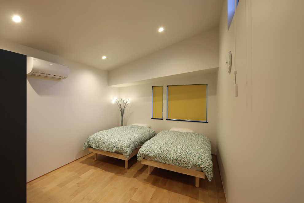 Mid-sized minimalist guest light wood floor, wallpaper ceiling and wallpaper bedroom photo in Tokyo with white walls and no fireplace